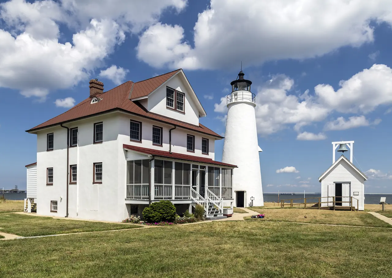 Cove Point Light and its white keeper's house under a summer sky in Lusby, Maryland.